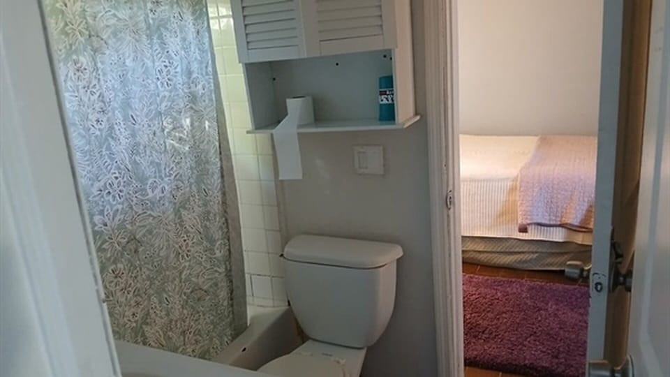 Bathroom with toilet, tub/shower, and bedroom access