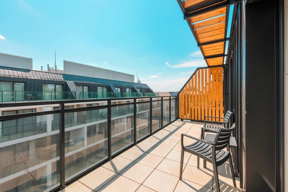 A balcony with outdoor seating and a glass railing. It offers a pleasant spot to enjoy fresh air.