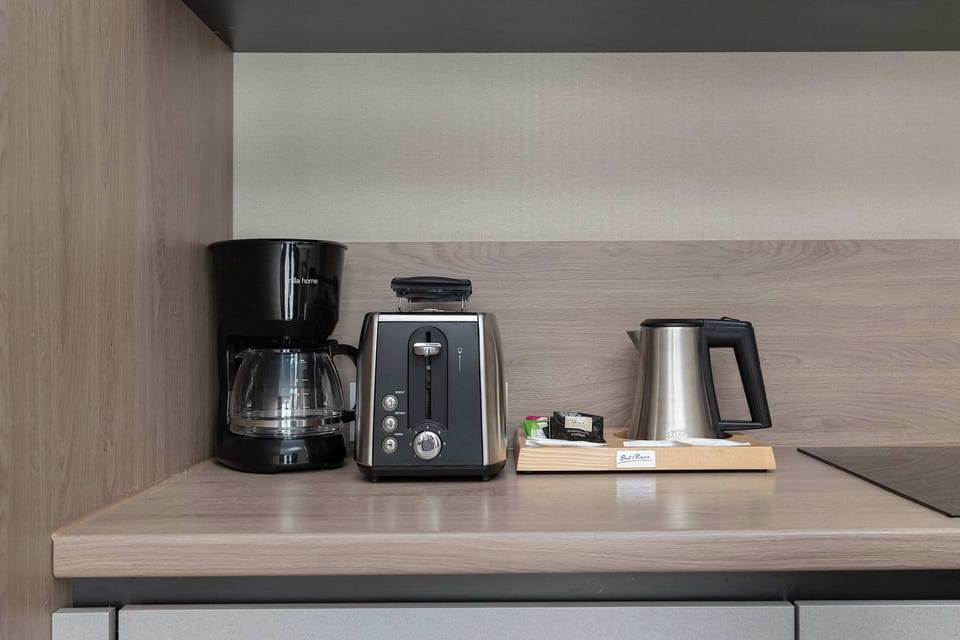 A close-up of the kitchenette countertop with a coffee machine, kettle, and toaster. Everything is neatly arranged for convenient daily use.