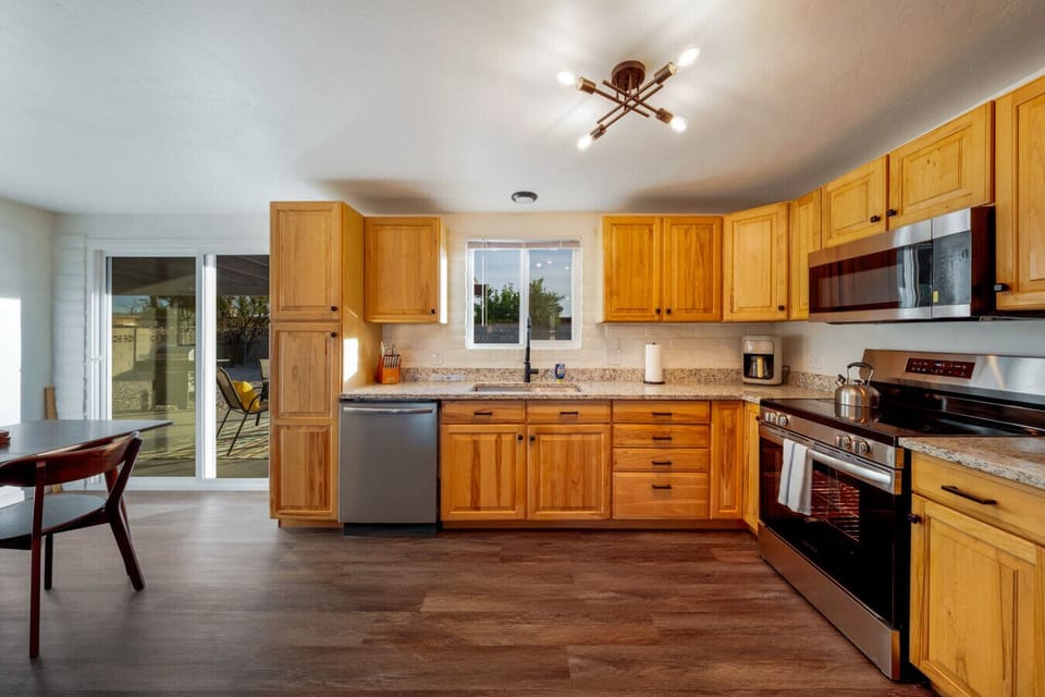 Updated, fully stocked kitchen with stainless steel appliances, plenty of storage space, and views of the lovely private backyard pool