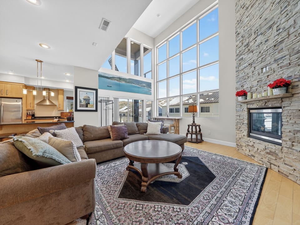 Sink into plush sectional seating by your stone fireplace, where floor-to-ceiling windows frame mountain views.
