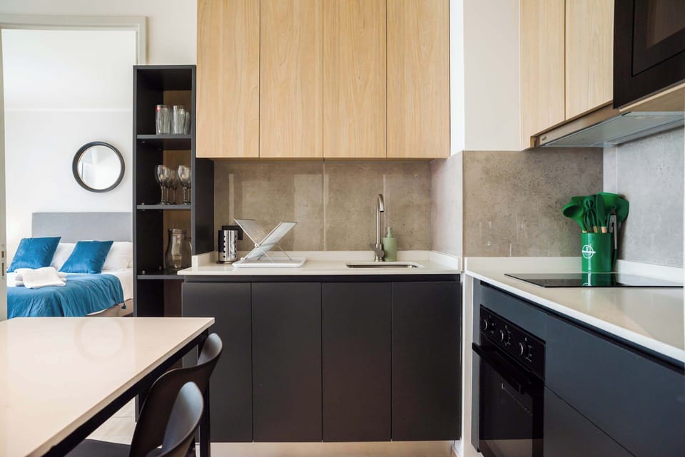 Modern kitchen with stylish cabinetry and a glimpse into a cozy bedroom, perfect for a seamless living experience.