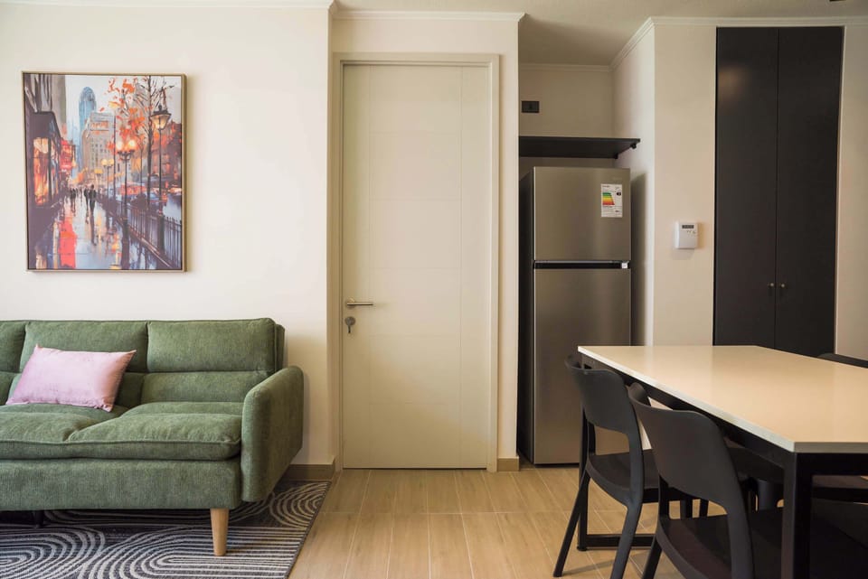 Living room with a green sofa, colorful cityscape artwork, and adjoining breakfast bar for relaxed meals and conversation.