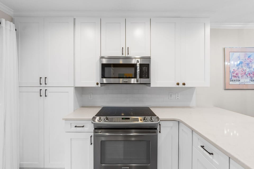 Glass top stove and oven, with top microwave. Cabinets galore filled with dinnerware, glassware, silverware, pots, pans - this kitchen has it all.