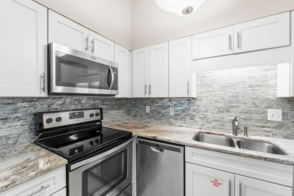 Kitchen offers double stainless sinks, microwave, dishwasher and stove/oven for easy meal prep. Plenty of cabinet space filled with dinnerware, drinkware, pots, pans and eating utinsels. A complete kitchen set up.