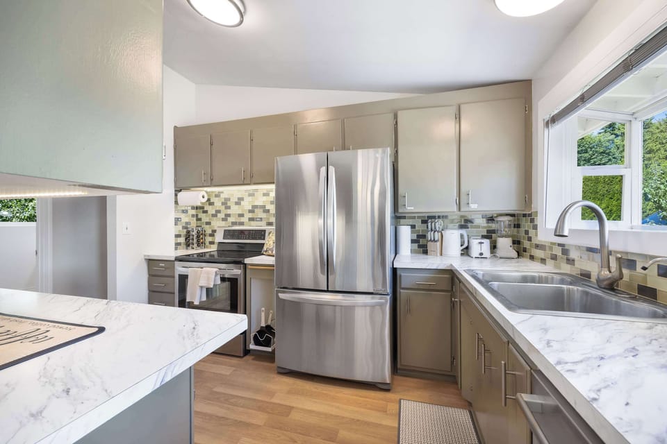 The kitchen boasts bright cabinetry, marble countertops, and an island for meal preparation or casual dining.