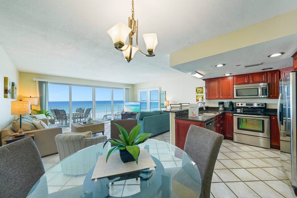 This beachfront condo in Destin features an open-concept kitchen, dining area, and Gulf-front living room with a private balcony overlooking the Emerald Coast.