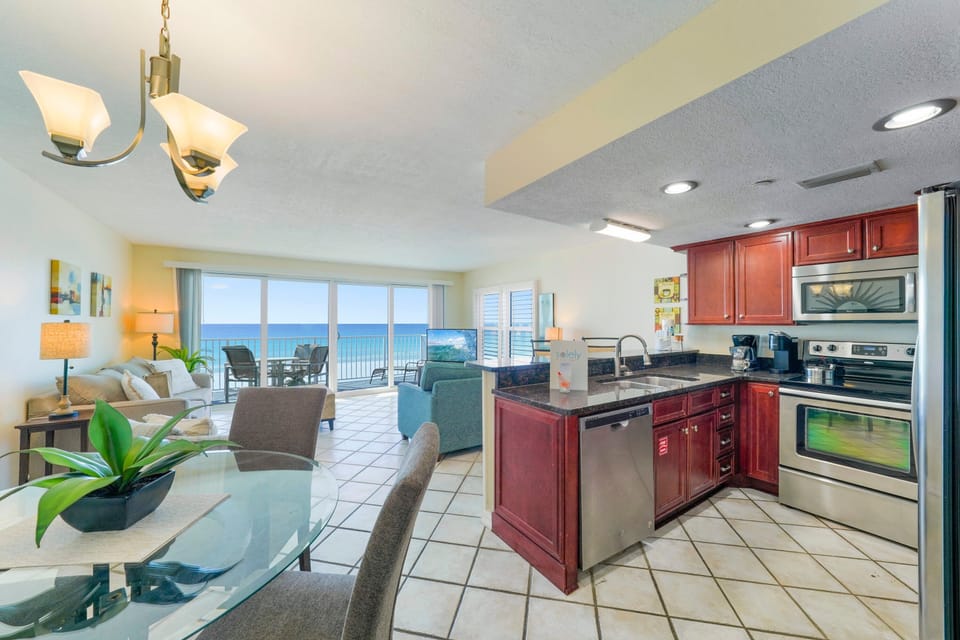 Open coastal living area at Cabana Club 308 in Destin, Florida, showcasing a fully equipped kitchen, dining table, and stunning ocean views of the white sand beaches.