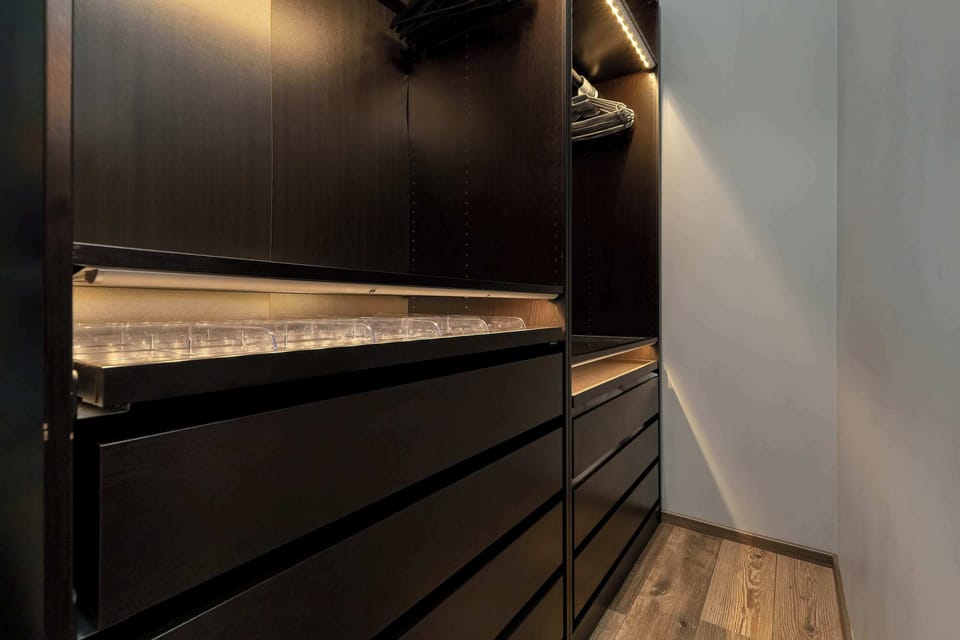 A practical walk-in wardrobe located in the bedroom, offering ample storage space. The design is modern and well-organized.