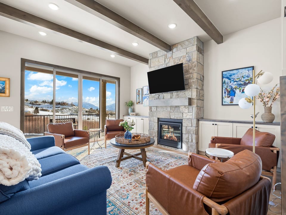 Primary living room at Summit View Lodge with large cozy gas fireplace, large smart TV, ample luxurious seating and a large amazing deck with unobstructed views of Mount Timpanogos