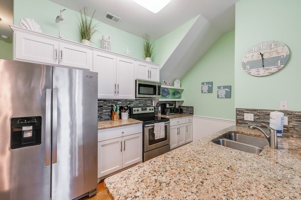 Your fully equipped kitchen features granite counters, stainless appliances, and stylish green walls—perfect for preparing memorable vacation meals together.