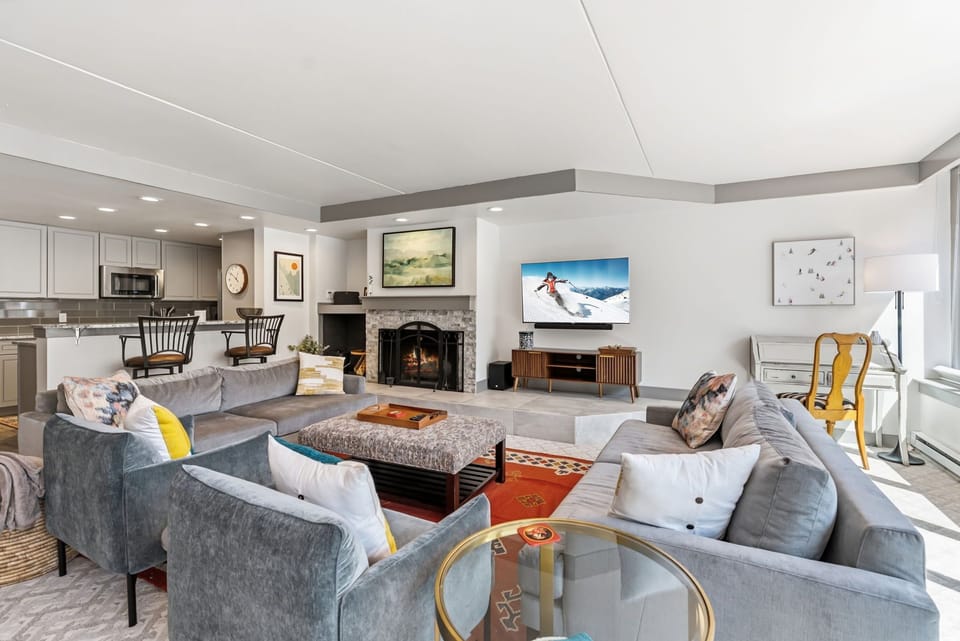 Relax in your spacious open-plan living area where plush seating faces a cozy fireplace, perfect for unwinding after mountain adventures.