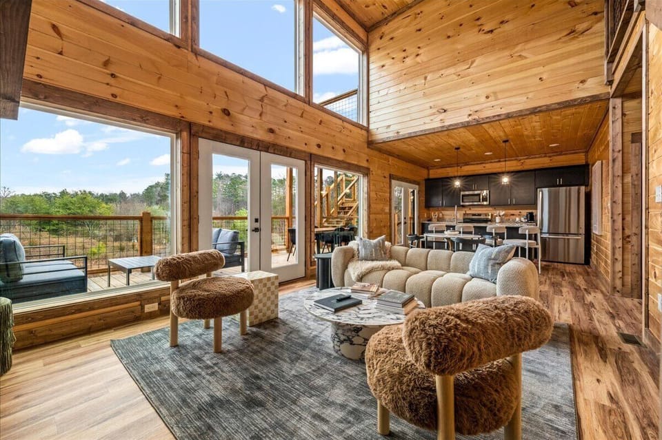 Unwind in your stunning timber retreat where soaring ceilings and floor-to-ceiling windows frame breathtaking forest views from your cozy living space.