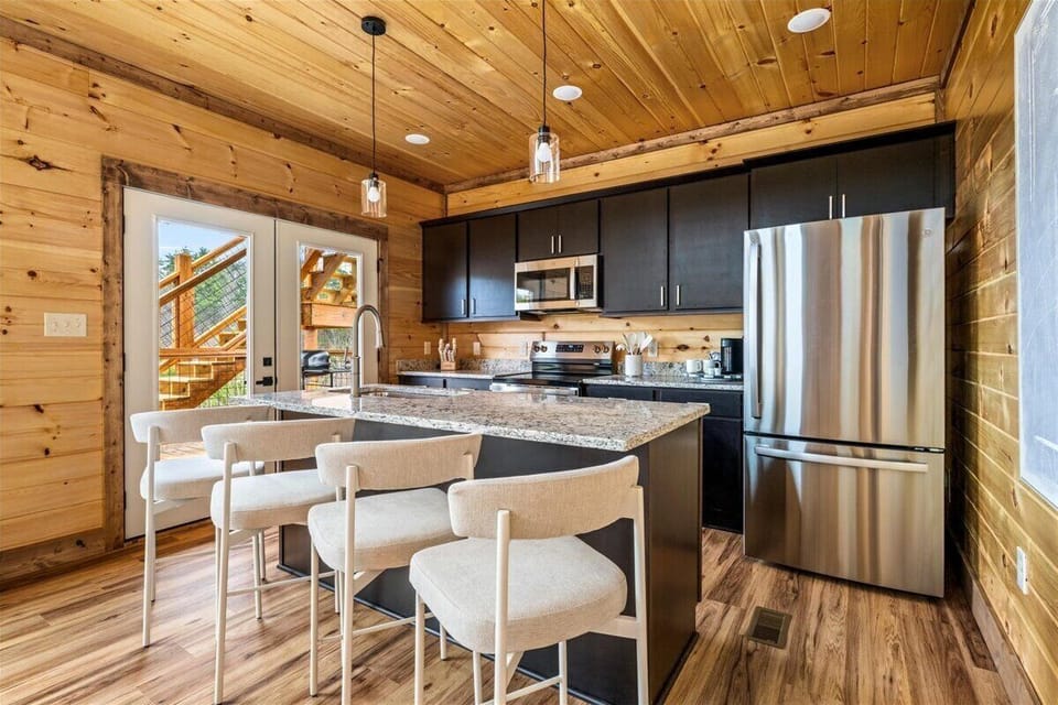 Your modern kitchen features granite countertops, stainless appliances, and warm wood cabin charm—perfect for preparing meals in mountain style.