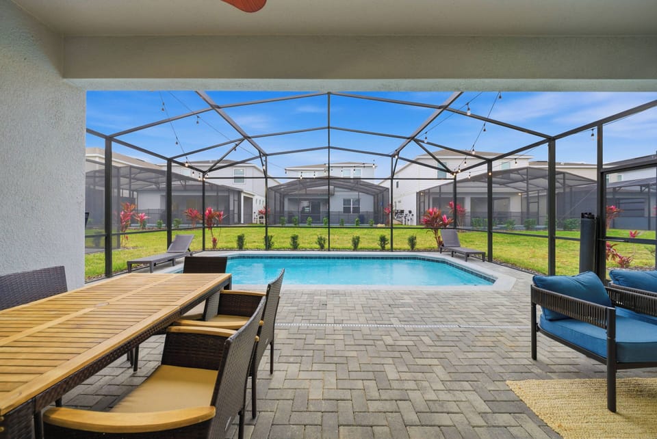 Experience a private paradise with a spacious outdoor area, highlighted by a shimmering pool and lush greenery. Relax at a stylish dining set, ideal for enjoying meals while basking in the sunshine and fresh air.