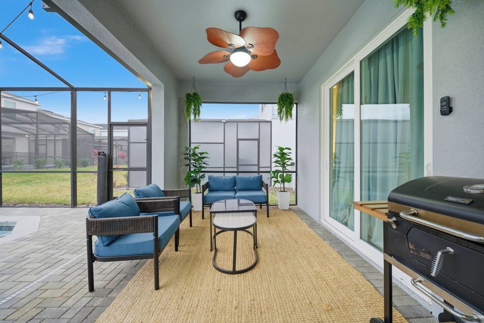 Step into a cozy outdoor lounge area featuring comfortable blue seating, perfect for relaxing afternoons. The warm wood accents and natural textures create a welcoming atmosphere, while the ceiling fan adds a refreshing breeze.