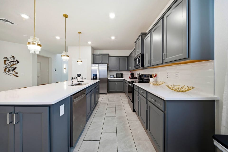 Discover the charm of our stylish kitchen featuring sleek gray cabinets and a spacious white countertop, perfect for meal prep or casual dining. Enjoy the inviting pendant lighting and modern appliances that make cooking a breeze.