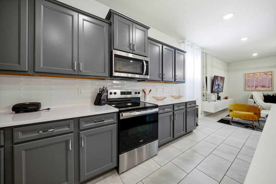 This bright, spacious kitchen with sleek gray cabinetry and white countertops is perfect for your culinary adventures, flowing seamlessly into the living area for shared moments and effortless entertaining.