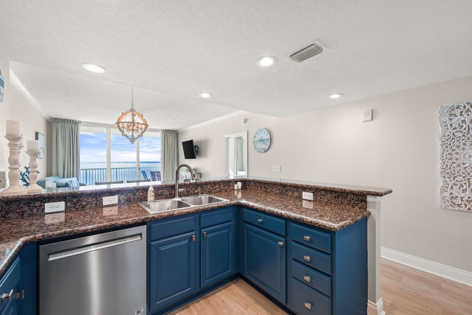 Your fully equipped kitchen features granite counters, stainless appliances, and stunning ocean views through floor-to-ceiling windows.