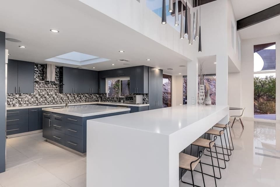 You'll love creating meals in this sleek, modern kitchen featuring a spacious island with bar seating, high-end appliances, and dramatic pendant lighting that sets the perfect mood for cooking and gathering.