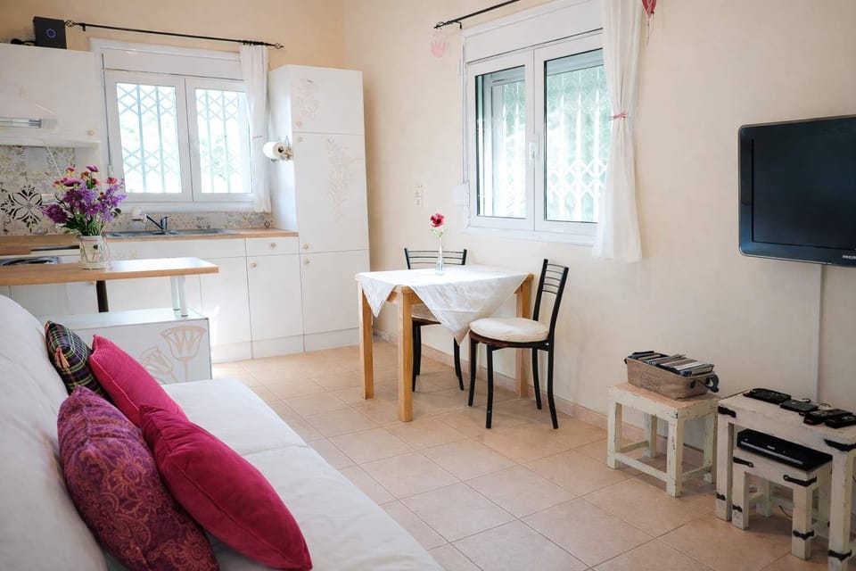 Bright living area with sofa, dining space, and TV, offering a comfortable setup for both relaxation and entertainment.