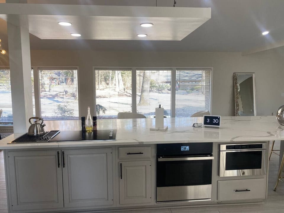 Bright kitchen with white cabinets, quartz countertops and oven