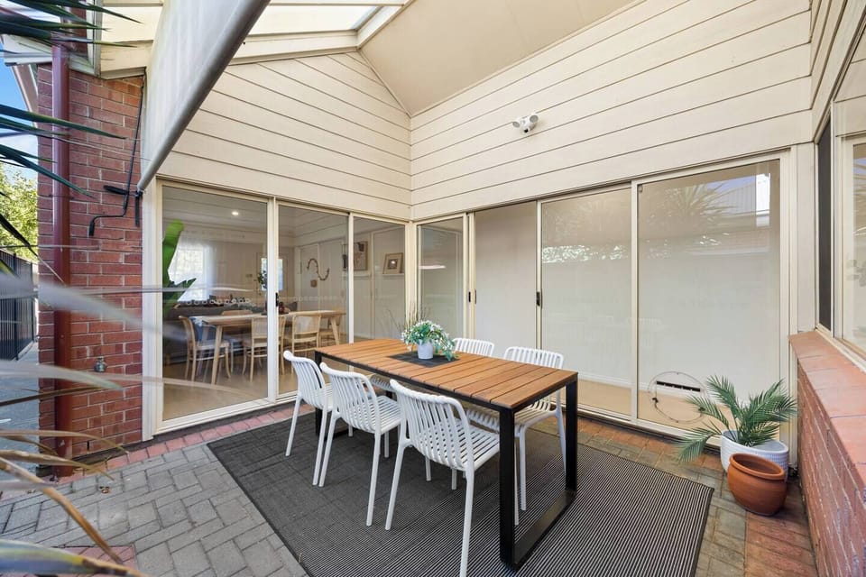 Dine outdoors on the private patio, where a generous table, fresh air, and an outdoor roller blind provide shade and comfort for long lunches and relaxed evenings.