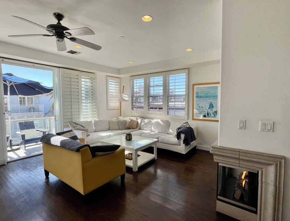 Sun-filled living room with comfortable seating, TV, and fireplace. 