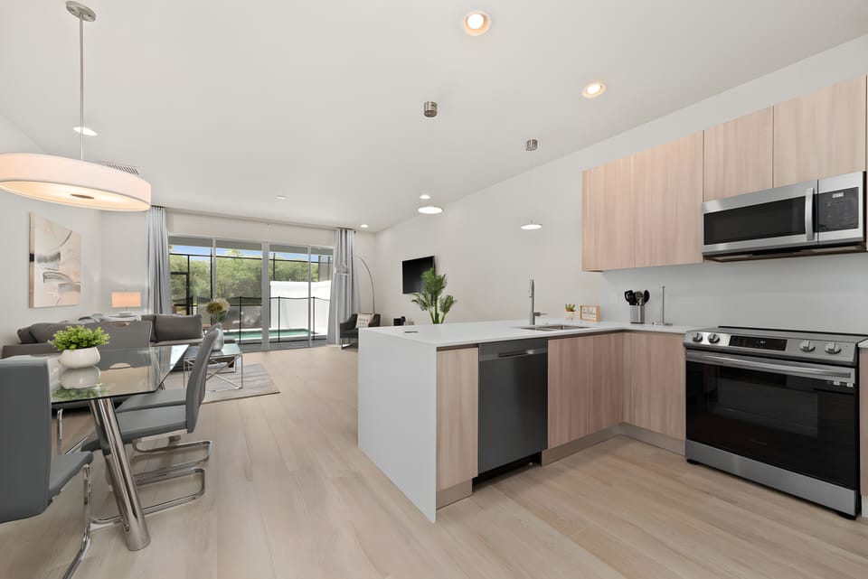 Welcome to this bright kitchen featuring sleek stainless steel appliances and warm wood cabinetry, balancing style and functionality. Enjoy the natural light from large windows that brighten the modern dining area.