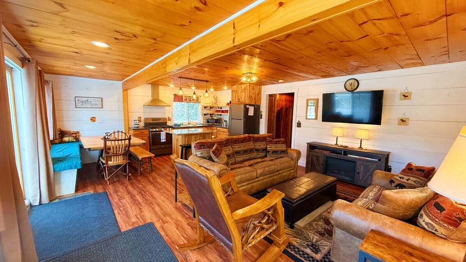 Spacious open-concept cabin living area with rustic furnishings, a fully equipped kitchen, and comfortable seating for memorable family gatherings.