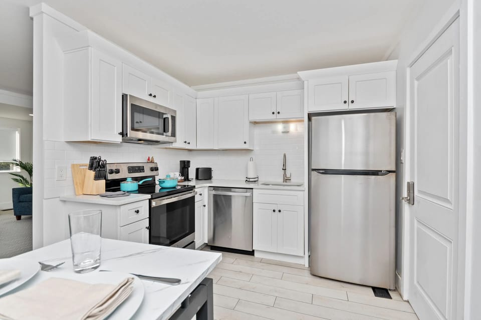 Fully equipped kitchen with stove, oven, microwave, dishwasher, fridge with freezer, coffee machine, a dining table, and essential cookware and dinnerware—perfect for easy meals and relaxed dining.