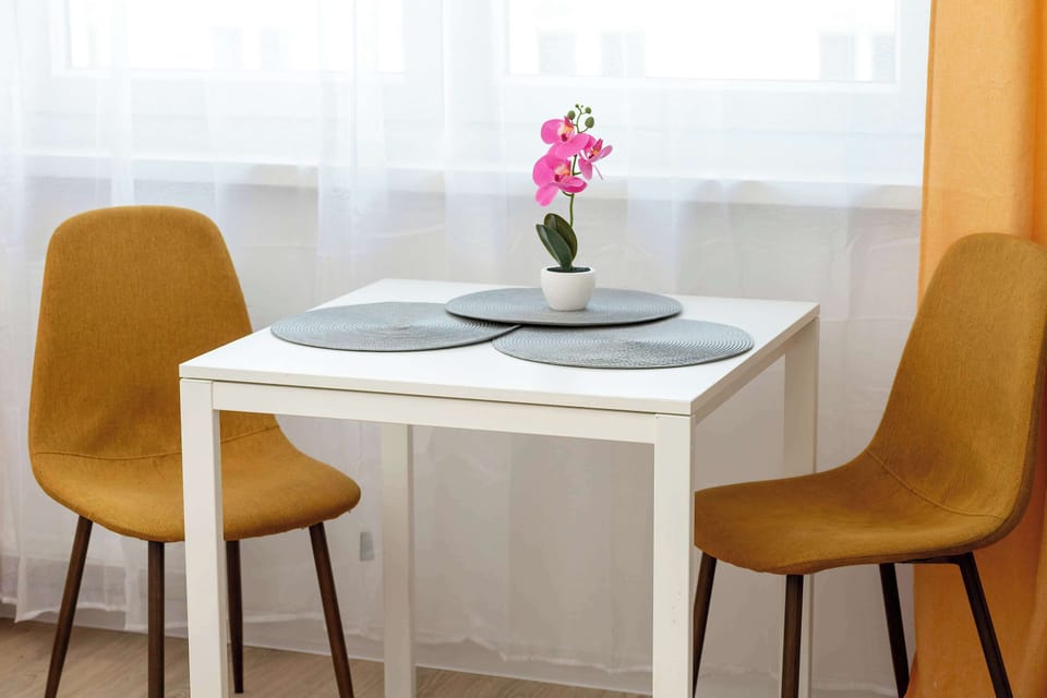 Stylish dining area with table, upholstered chairs, and decorative plant centerpiece.