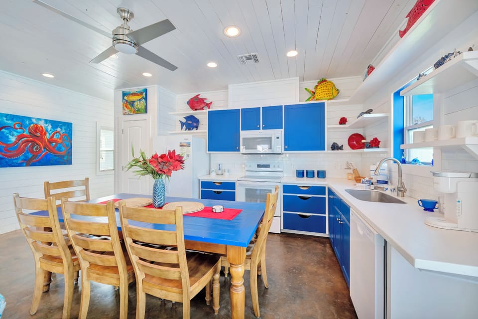 Your coastal-themed kitchen awaits with vibrant blue cabinets, full appliances, and a dining table perfect for morning coffee or family meals.