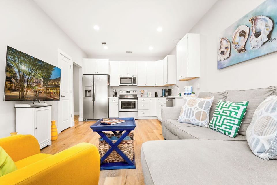 Relax in your stylish open-concept space featuring a plush sofa, vibrant yellow chair, and fully equipped kitchen with modern appliances.