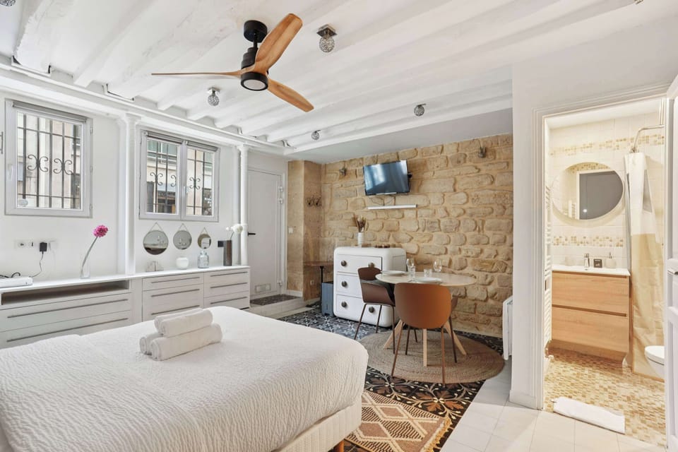 Pièce de vie lumineuse avec un lit queen size, TV et table à manger