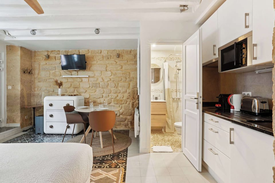 Pièce de vie lumineuse avec un lit queen size, TV et table à manger. Cuisine équipée et fonctionnelle ouverte 