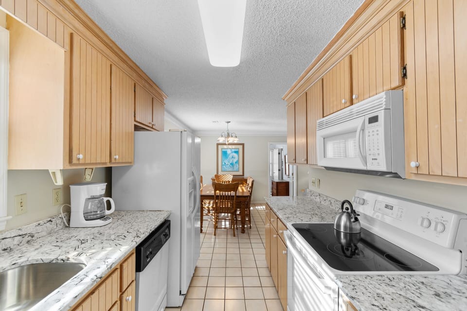 Your fully equipped galley kitchen features granite countertops, modern appliances, and warm wood cabinets for creating memorable meals.
