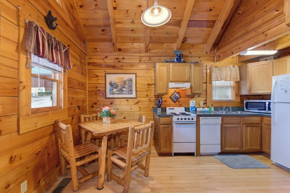 Gather around your rustic log dining table in this cozy cabin kitchen, where wood beams frame memorable meals together.