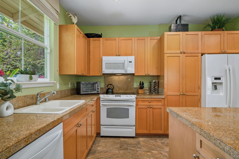 Cook your favorite meals in this fully equipped kitchen with granite countertops, warm wood cabinets, and modern appliances.