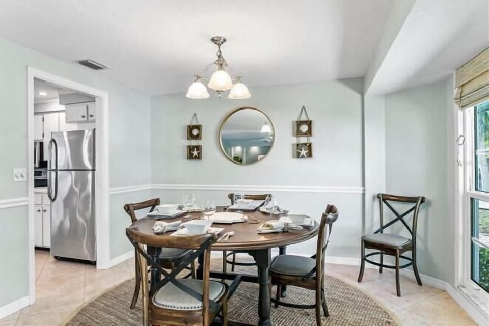 Gather around your elegant dining table with charming coastal touches, where morning coffee and evening meals become memorable moments in this light-filled space.