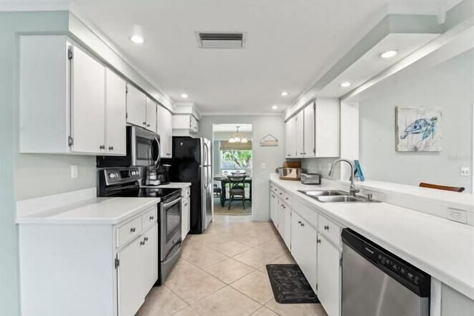 Your fully equipped kitchen awaits with white cabinets, modern appliances, and bright lighting, perfect for preparing memorable meals during your stay.