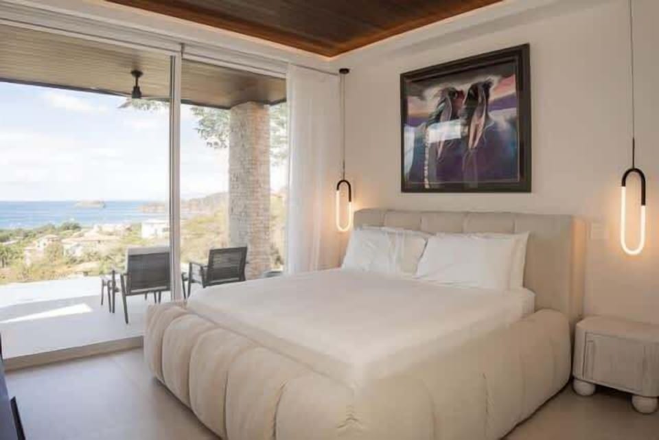 Luxury king bedroom with private balcony, TV, and ocean views