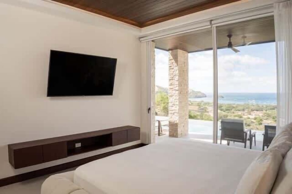 Luxury king bedroom with private balcony, TV, and ocean views