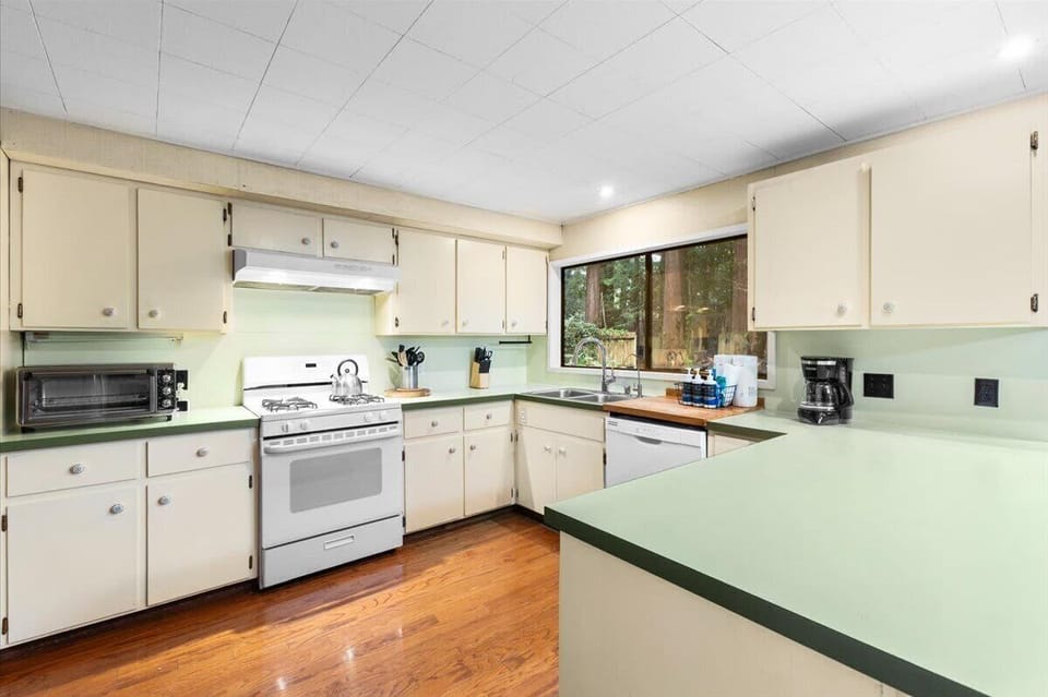 Fully equipped kitchen featuring a breakfast bar, garden window, and forest views.