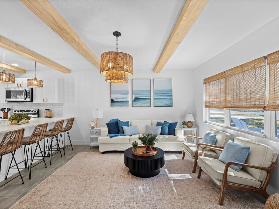 Serene beach-inspired lounge with blue accents, wicker barstools, and natural light.
