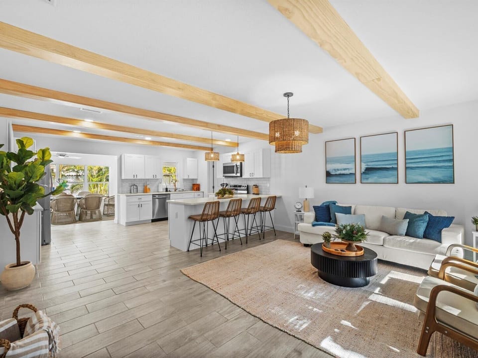 Serene beach-inspired lounge with blue accents, wicker barstools, and natural light.
