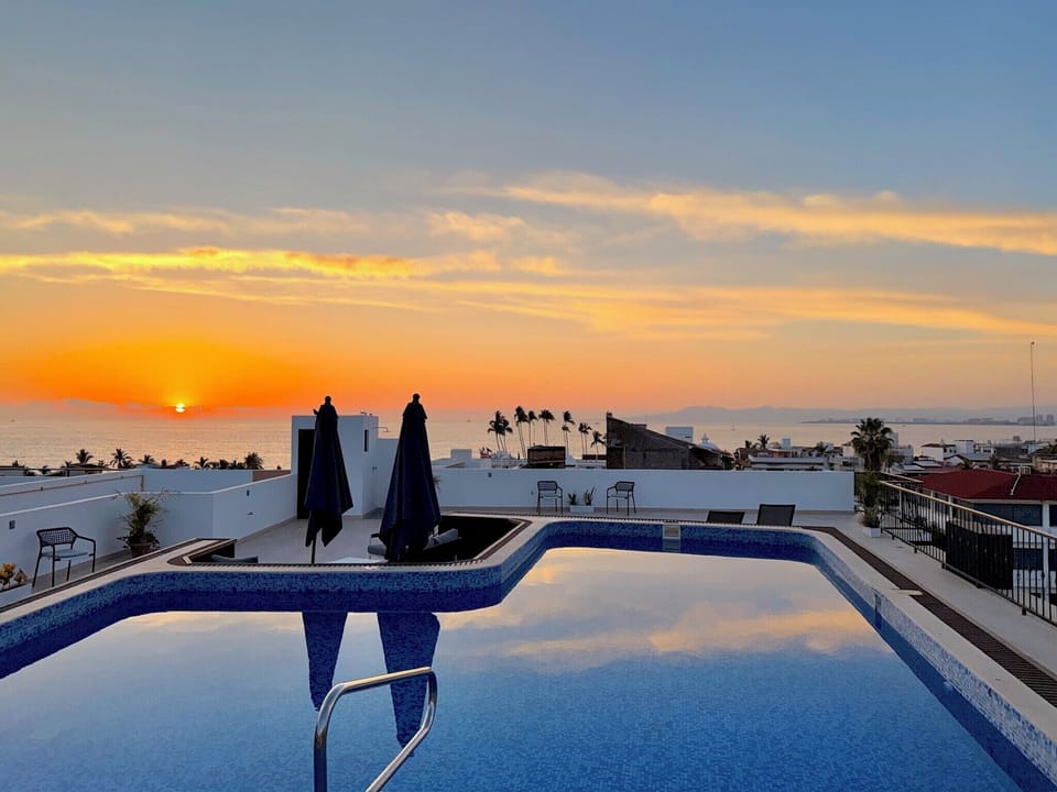 Rooftop pool with seating and lounge chairs. 