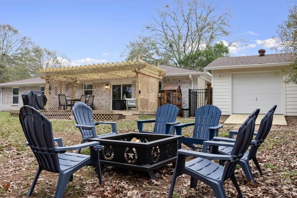 Backyard fire pit area with seating, open lawn, and a clear view of the deck and pergola for easy indoor-outdoor flow.