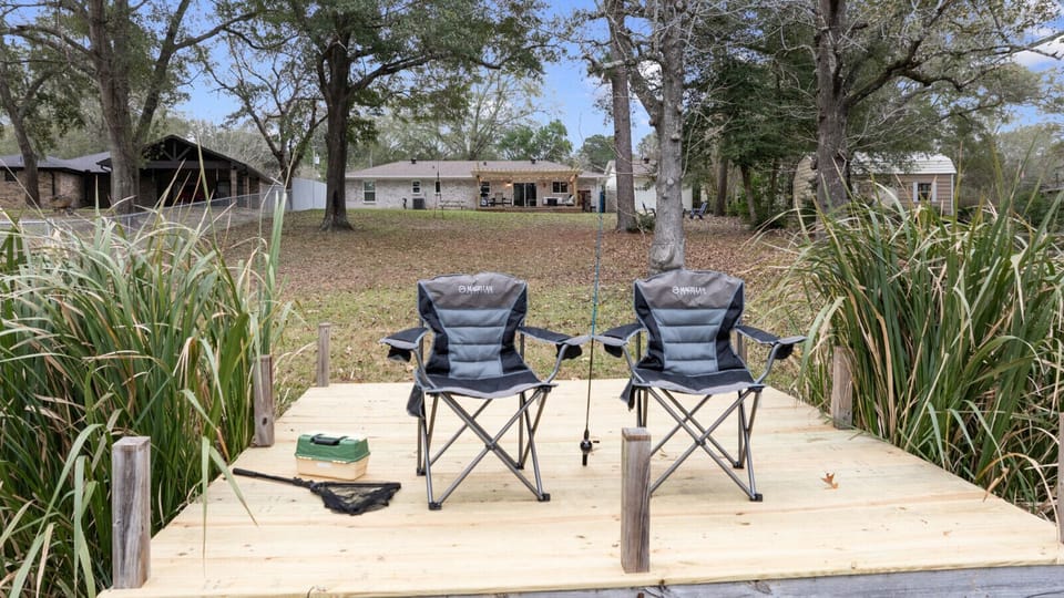 Cozy fishing dock with two comfortable chairs, surrounded by lush reeds. Perfect spot to relax, fish, and enjoy peaceful views of the water and nature right from your backyard.