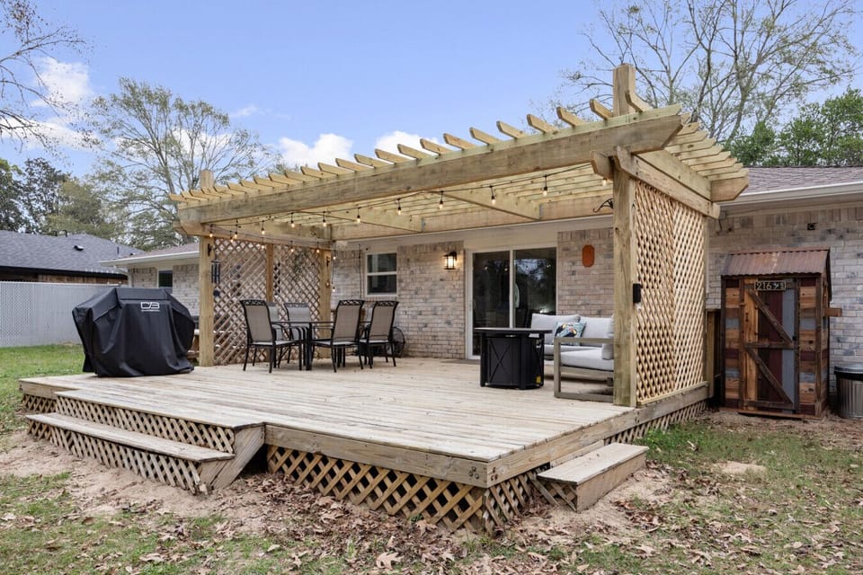 Spacious backyard deck with pergola, string lights, outdoor dining, and lounge seating—ideal for gathering, grilling, or unwinding outdoors.